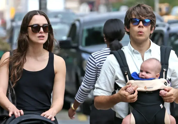 Keira Knightley z mężem i ich maleńkim dzieckiem w nosidełku, spacerując po ulicy.
