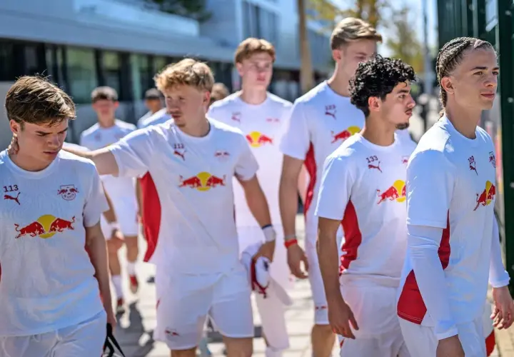 Junge Fußballer des RB Leipzig U12 Teams in weißen Trikots mit dem Bullen-Logo gehen gemeinsam.