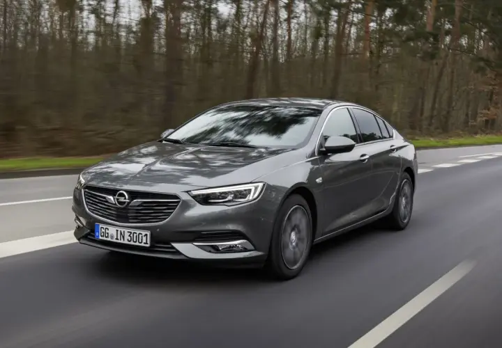 Grå Opel Insignia kör på en väg genom en skog. Kanske ett opel insignia problem med att hitta rätt väg?