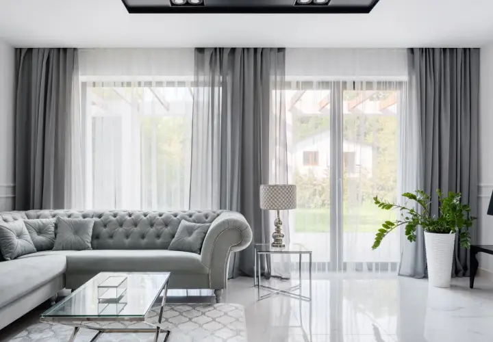 Elegancki salon z szarymi zasłonami do sufitu, które pięknie otulają okna, tworząc przytulną atmosferę.