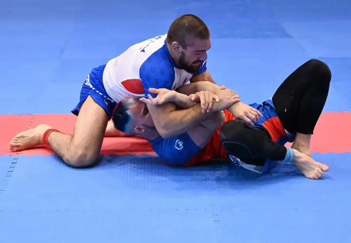 Dwóch mężczyzn walczy na macie. Jeden klęczy, drugi leży. To właśnie bjj co to za sport?