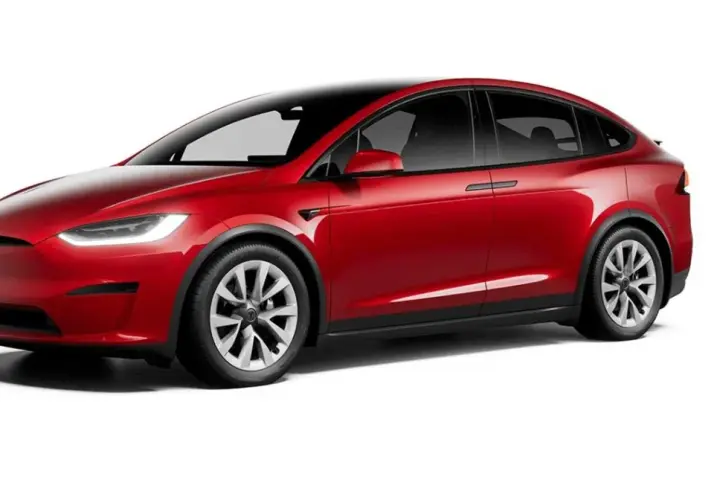 Czerwony Tesla X z czarnym dachem i przyciemnianymi szybami, prezentujący nowoczesny design i elektryczną moc.