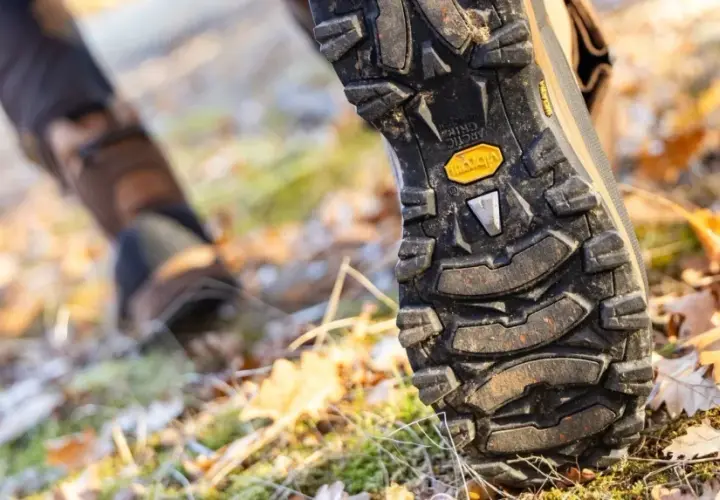 Close-up of a hiking boot sole on a forest floor. Learn how to break in hiking boots for comfortable adventures.