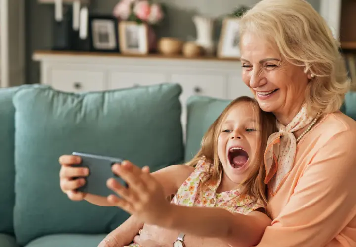 Großmutter und enkel kinder machen ein Selfie. Sie lachen beide vor Freude.