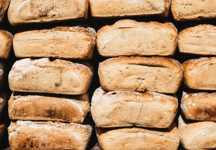 Stos chleba, który zastanawia, czy pies może jeść chleb. Każdy bochenek ma złocistą skórkę i lekko posypany mąką.