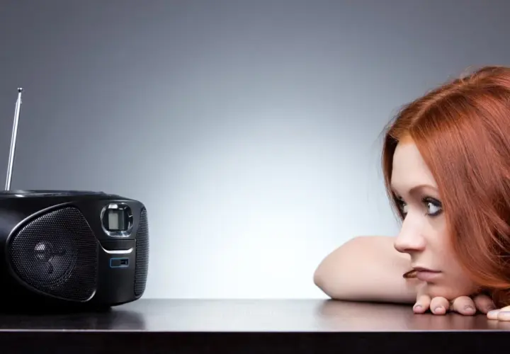Rudowłosa dziewczyna wsłuchuje się w radio. Może właśnie słyszy ulubioną piosenkę z Vox FM Warszawa.