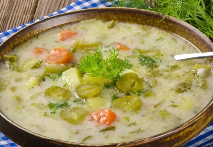Zupa ogórkowa z ziemniakami i marchewką, ozdobiona koperkiem. Pamiętaj, jakiej przyprawy nie wolno dodawać do zupy ogórkowej, by nie zepsuć jej smaku!