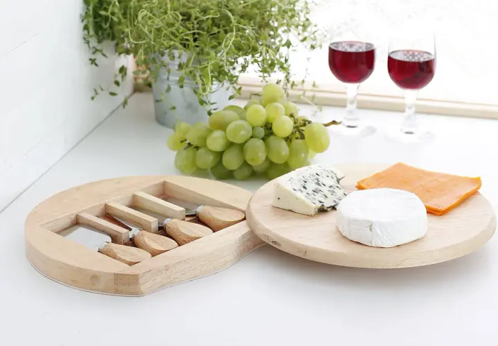 Jak przygotować deskę serów do wina: dobór smaków i tekstur. Ser pleśniowy, brie i cheddar z winogronami i kieliszkami wina.