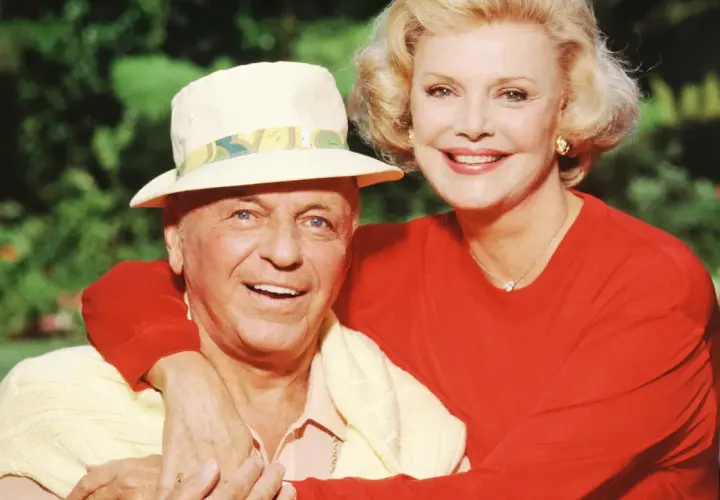 Frank Sinatra z żoną Barbarą, uśmiechnięci, w słoneczny dzień na tle zieleni.