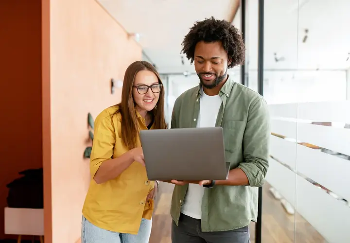 A woman and man discuss public administration vs public policy on a laptop.