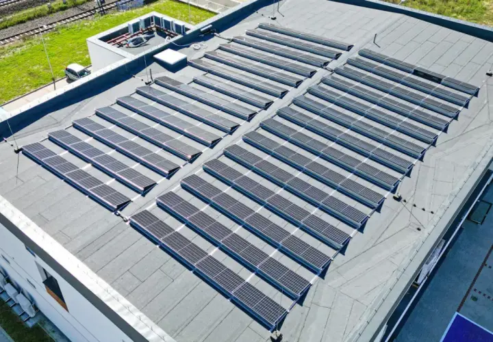Nowoczesny dom z płaskim dachem pokryty rzędami paneli słonecznych, które czerpią energię ze słońca.