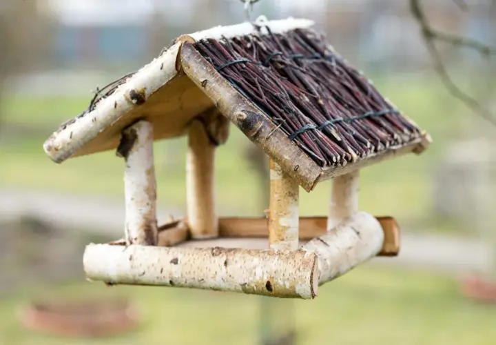 Ein selbstgebautes vogelfutterhaus aus Holz und Zweigen, bereit für gefiederte Gäste.