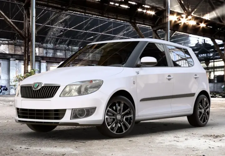 Biała Skoda Fabia z czarnymi felgami stoi w opuszczonej hali. Rozmiar opon idealnie pasuje do sportowego charakteru auta.
