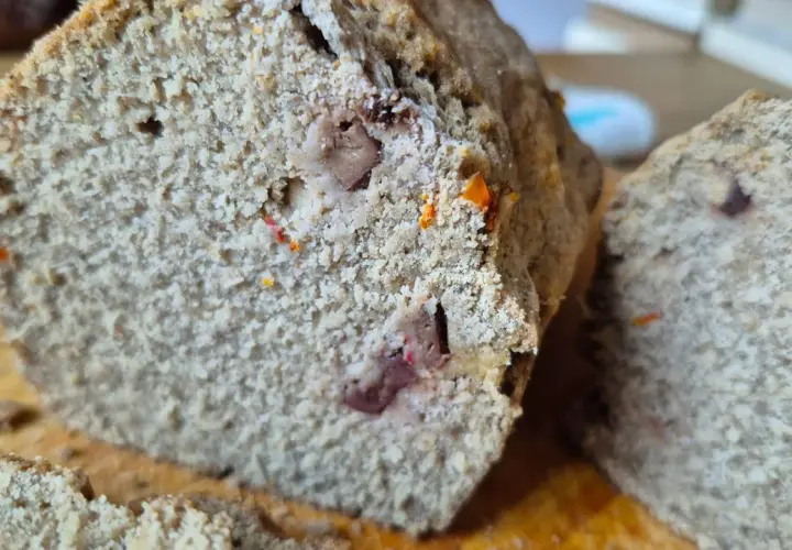 Rebanada de pan sin gluten con trozos de frutos secos y un toque anaranjado.