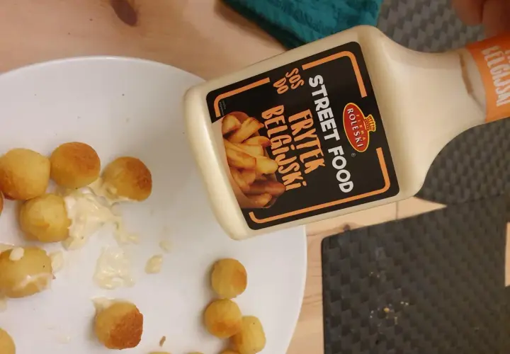 Kula frytek na talerzu, obok butelka sosu belgijskiego Street Food.