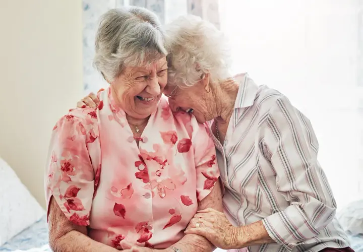Zwei lachende Seniorinnen, die sich umarmen. Ein schönes Beispiel, wie man neue Freunde finden ab 60 kann.