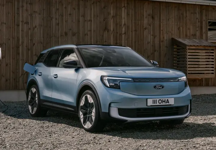 Blå elbil, en Ford Explorer, laddas vid en laddbox framför ett trähus. En spännande ford explorer test.