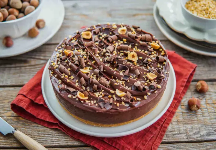 Delizioso cheesecake alla nutella, ricoperto di riccioli di cioccolato e nocciole tostate.