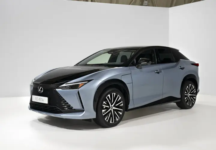 Elegancki, niebieski Lexus RZ 450e z czarnym dachem i futurystycznymi felgami stoi na białym tle.