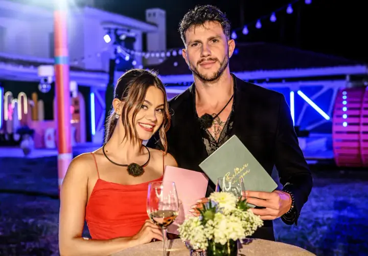 Para z Love Island, która wygrała, pozuje z uśmiechem. Ona w czerwonej sukience, on w czarnym garniturze.