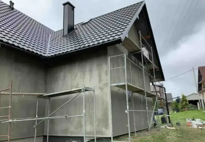 Dom w trakcie prac elewacyjnych, rusztowania wokół ścian. Zastanawiasz się, ile kosztuje elewacja domu?