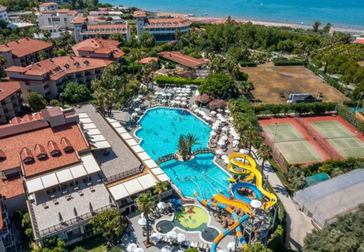 Widok z lotu ptaka na Alba Resort Hotel z basenami, zjeżdżalniami wodnymi, kortami tenisowymi i plażą w tle.