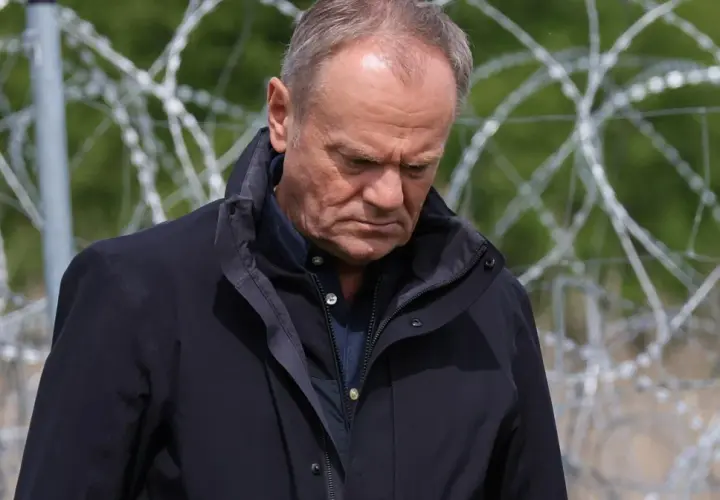 Mężczyzna w ciemnej kurtce patrzy w dół, za nim drut kolczasty. Czy to symbol jego hipokryzji?