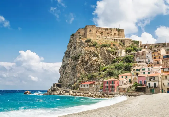 A picturesque coastal village with colorful houses clinging to a cliff, topped by an ancient castle. This is a must-see destination for anyone wondering where to go in Calabria.