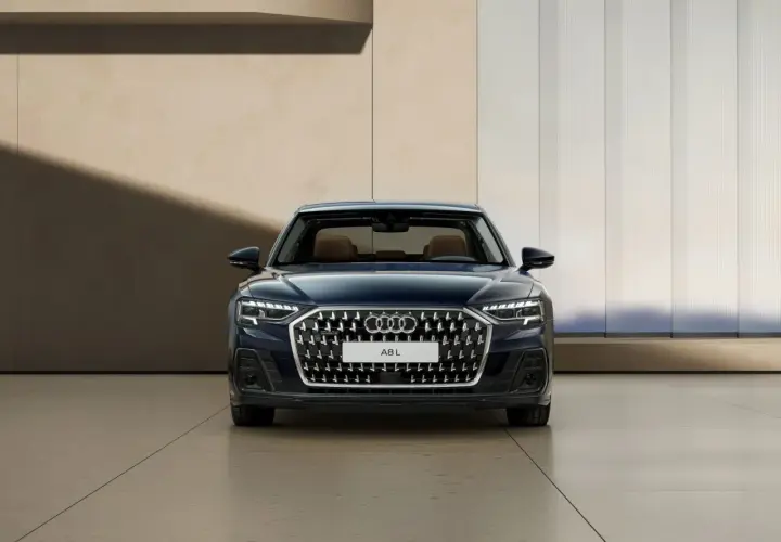 Elegancki, ciemnoniebieski Audi A8 2025 z brązowym wnętrzem prezentuje się na tle nowoczesnej architektury.