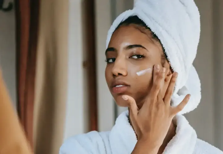 Mujer con toalla en la cabeza aplicándose crema para combatir la piel seca.