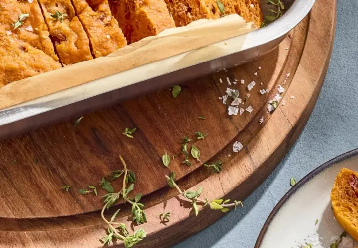 Frisch gebackene focaccia mit tomaten, bestreut mit Meersalz und Thymian, bereit zum Genießen.