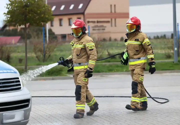 Strażacy w akcji, jeden z węża wodnego. Zastanawiasz się, ile zarabia strażak? To praca pełna wyzwań.
