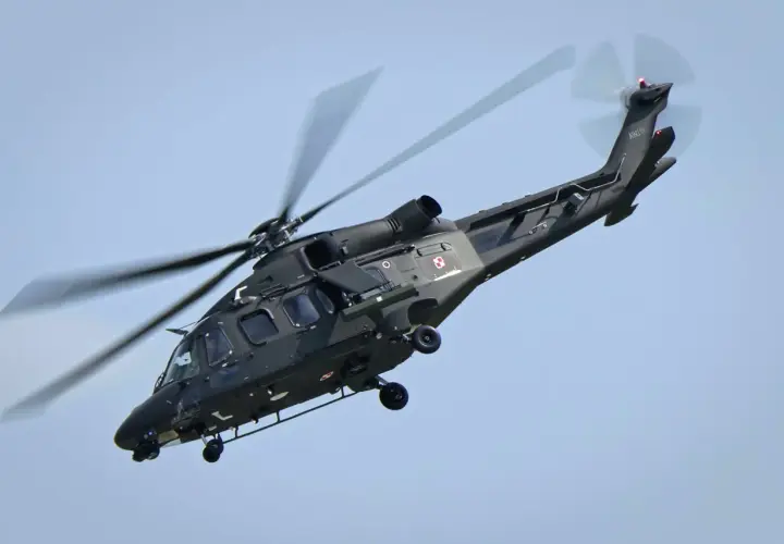 Ciemnozielone helikoptery wojskowe z polskimi szachownicami w locie.