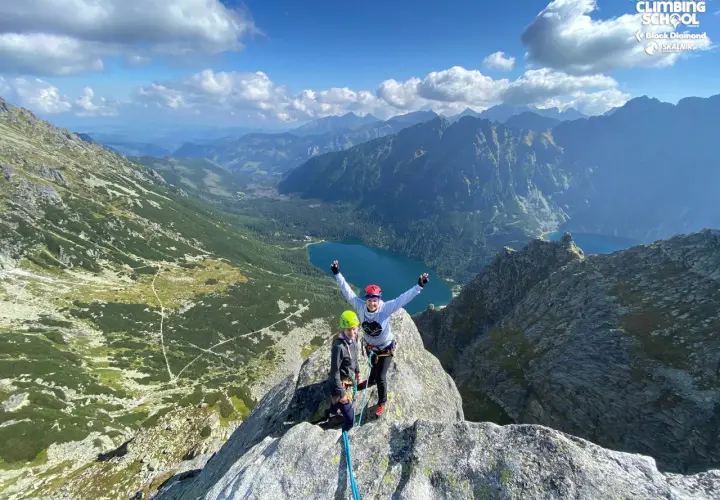 Dwóch wspinaczy na szczycie, radość po udanej wspinaczce. W tle malownicze Tatry i jezioro.