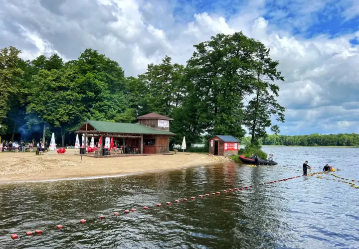 Plaża i jezioro w Szczecinku, z budynkami gastronomicznymi i ludźmi na wodzie. Idealne miejsce na letnie atrakcje.