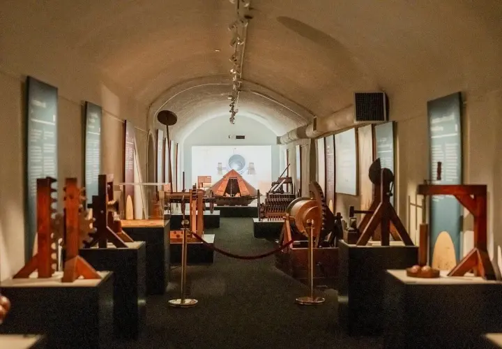 Maquettes d'inventions de Léonard de Vinci exposées dans un couloir voûté, une invitation à explorer le musée Léonard de Vinci à Rome.