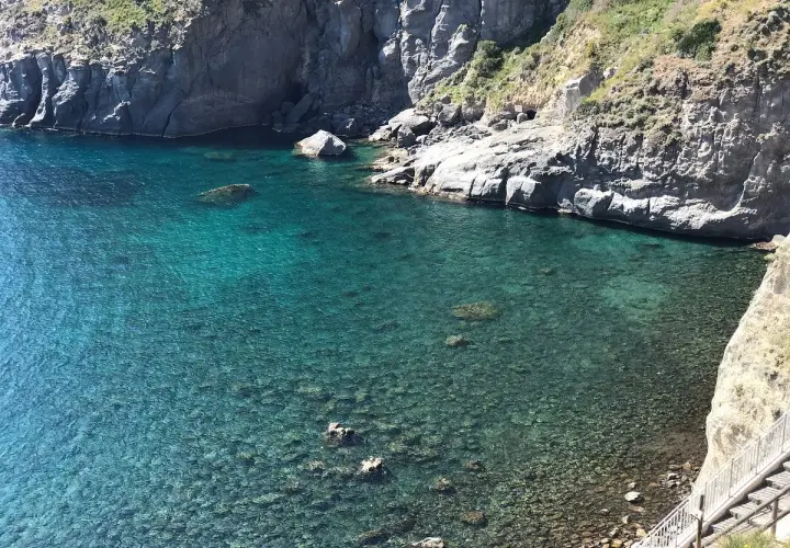 Acque cristalline e scogliere a picco a Ischia. Un angolo di paradiso dove la spiaggia incontra l'acqua calda, invitando al relax.