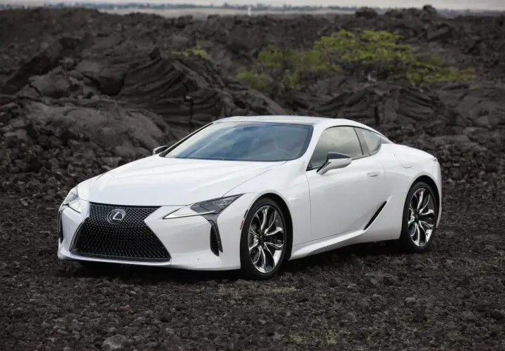 Biały Lexus LC 500 na tle wulkanicznych skał.