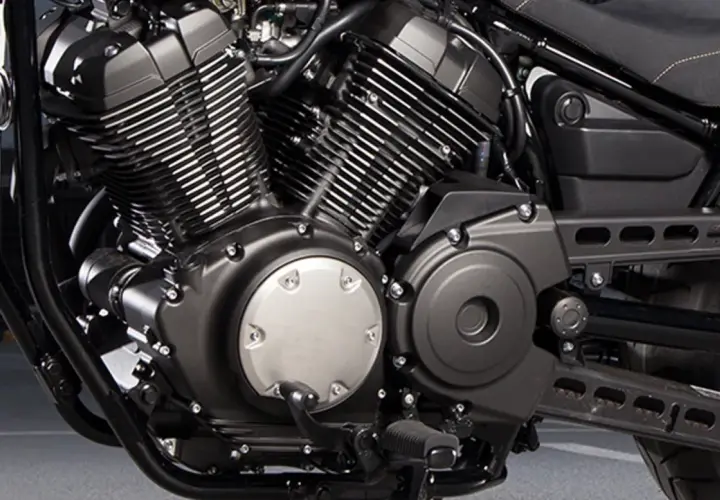 Silnik V-twin motocykla Yamaha XV950, z charakterystycznymi żebrowanymi cylindrami i czarnymi osłonami.