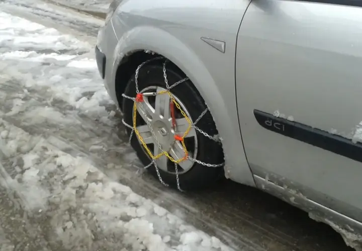El coche está en la nieve, listo para circular cuando se ponen las cadenas de nieve.