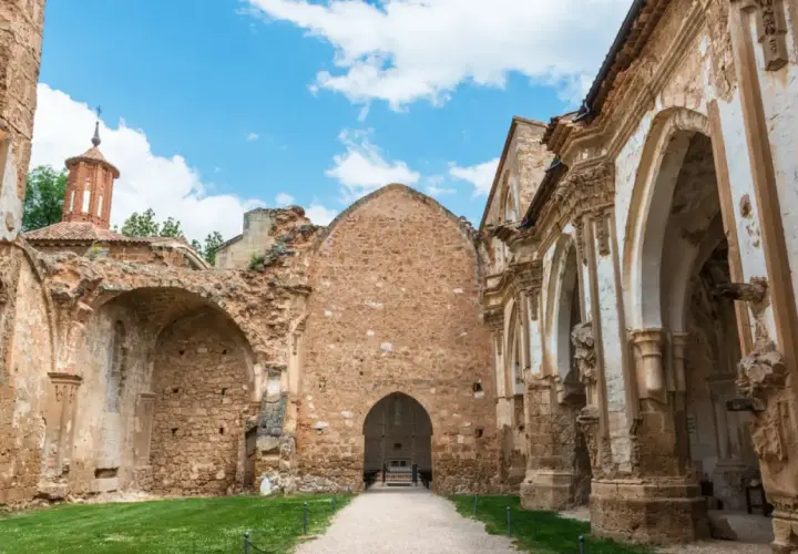 Ruinas de un antiguo convento, lugar donde se rodó Traitors España. El cielo azul con nubes contrasta con la piedra erosionada.