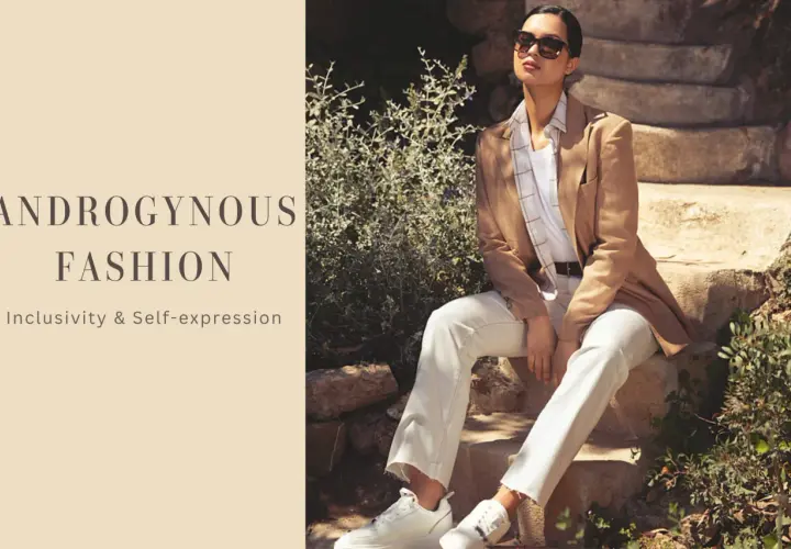 Modello androgino con blazer cammello, pantaloni bianchi e sneakers, su gradini di pietra.