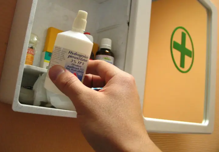 Ręka wyjmuje z apteczki butelkę z napisem "Hydrogenium peroxydatum 3% (Wodoru nadtlenek 3%) Syn. Woda utleniona". Idealna do walki z pleśnią.