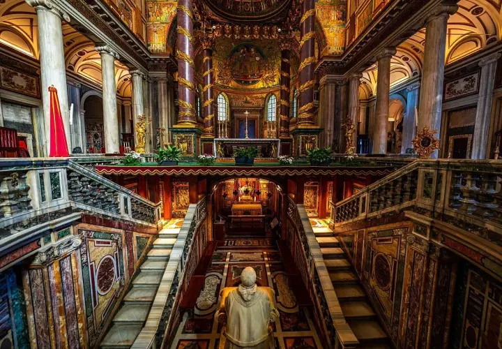 Interno della chiesa San Pietro a Roma, con scale marmoree, mosaici dorati e un altare imponente.