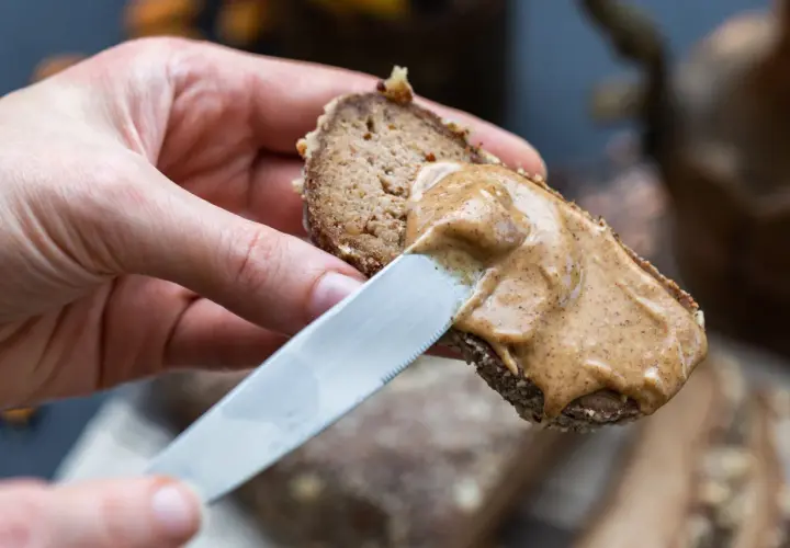 Mano spalma crema di nocciole su pane integrale. Ottima per conoscere i crema di nocciole valori nutrizionali.