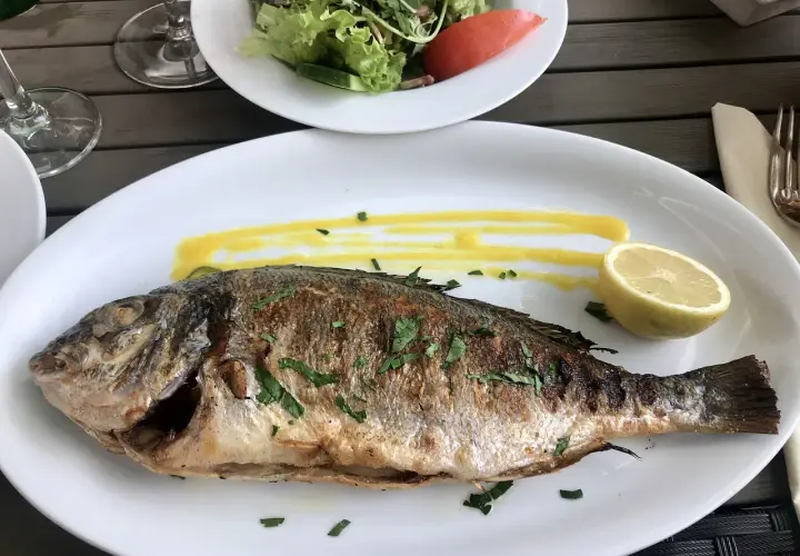 Dorade entière grillée à la plancha, sauce jaune, quartier de citron. Parfait pour le temps de cuisson.