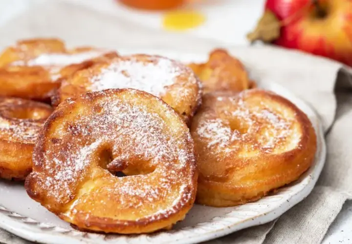 Délicieux beignets aux pommes saupoudrés de sucre glace, prêts à être dégustés.
