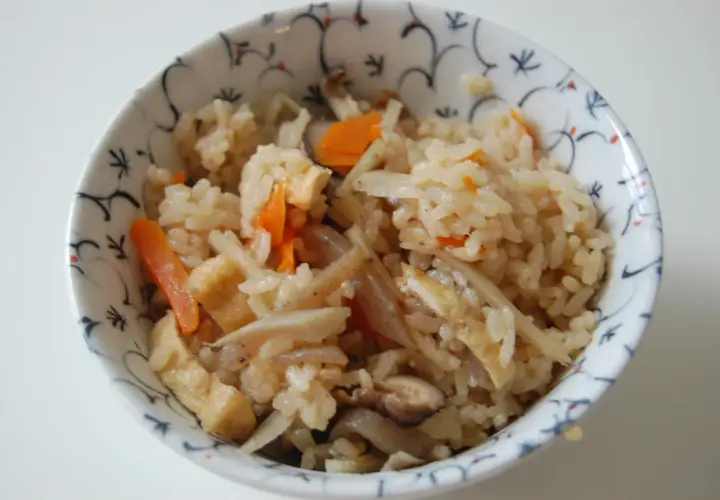 A bowl of gomoku rice, a Japanese mixed rice dish, filled with fluffy rice, tender carrots, shiitake mushrooms, and fried tofu.