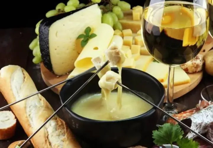 Un délicieux vin accompagne une fondue au fromage, avec du pain, des pommes de terre et de la charcuterie.