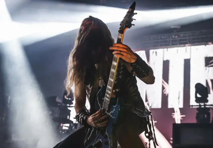 Pantera w Polsce: gitarzysta z długimi włosami gra na scenie, w tle wielki napis z nazwą zespołu.